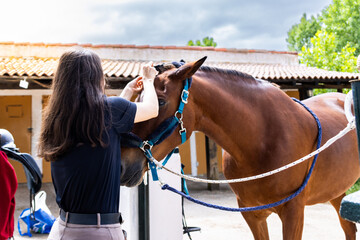 Woman braiding horse's mane in stable courtyard