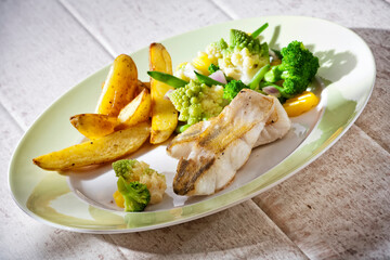 Healthy dish with pike-perch, potato wedges, broccoli and romanesco cabbage