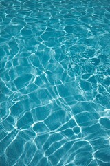 Fototapeta premium Close-up of clear blue water in a swimming pool with sunlight creating patterns on the surface.
