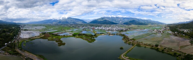 Fototapeta premium Aerial view of lush valley with rice fields and mountains