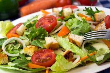 healthy and fresh mixed salad with tomato, croutons, orange bell pepper, onion rings, julienne carrot, cucumber slices