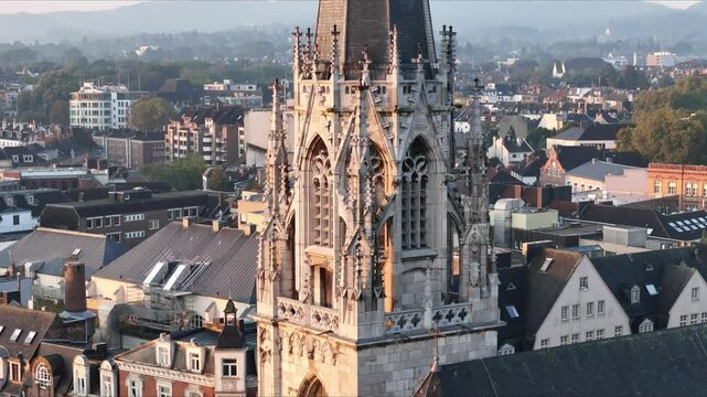 Drone view of the Gothic St. Foillan Church's tower surrounded by other buildings at sunset