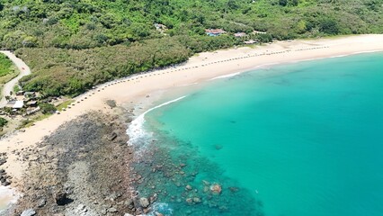 Aerial view of a tropical beach with turquoise water and lush greenery.