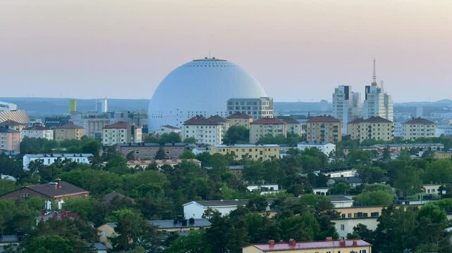 Stockholm buildings with trees and the Globe Arena in the background with pink sky at dusk in Sweden