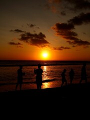 Fototapeta premium Silhouettes of people enjoying a beach sunset.