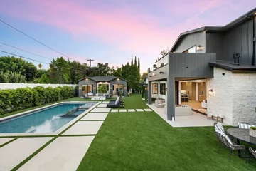 Fototapeten Lila Modern home exterior with pool and seating under pink sunset sky.  © Wirestock
