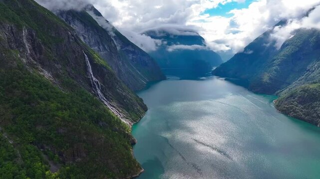 mountains landscape and fog surrounding a tranquil body of water in the Geiranger Fjord of Norway