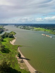 Aerial view of a river landscape with a cargo ship and lush greenery.