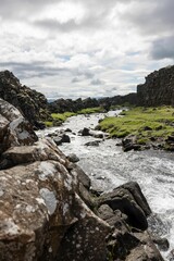 Scenic view of a rocky river flowing through a valley under a cloudy sky.