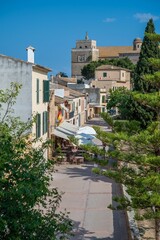 Fototapeta premium Picturesque street in a village with outdoor cafes and historic architecture under a clear blue sky