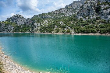 Turquoise lake surrounded by rocky mountains and greenery.