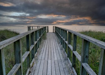 Wooden boardwalk to ocean at sunset