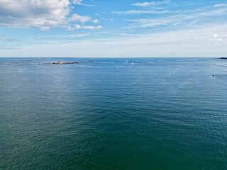 Ocean view with island and lighthouse under blue sky.