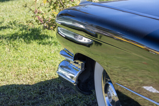 Cadillac coupe deville reflecting grass and trees on a sunny day