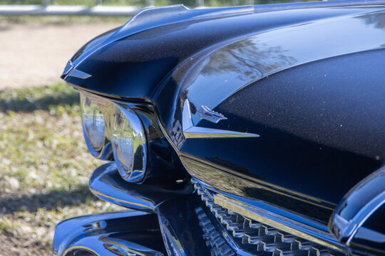 Close up of a black cadillac coupe deville showing the hood ornament and headlight