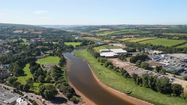Aerial of River Taw surrounded by green fields and buildings on a sunny day in Barnstaple, England