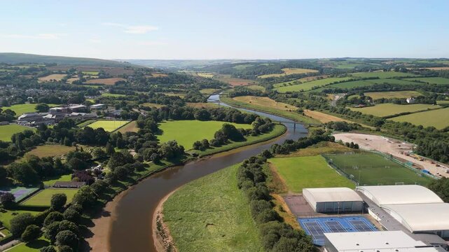 Aerial view over the River Taw surrounded by green fields and buildings on a sunny day in Barnstaple