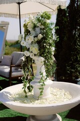 Elegant floral arrangement with white roses and greenery in a decorative outdoor setting
