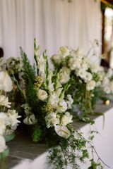 Elegant floral arrangements with white flowers in vases on a table in a wedding venue