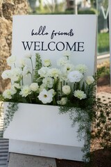 Welcoming sign adorned with white flowers and greenery © Wirestock