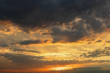 Dramatic sunset sky with vibrant orange and yellow hues beneath dark clouds