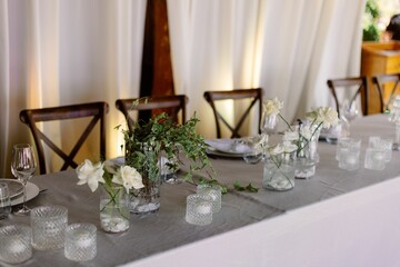 Elegant wedding table setting with white roses, glassware, and candles