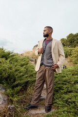 A dapper man in autumn attire poses gracefully amidst a colorful field, embracing the season's charm.