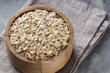 Oat Flakes in Wooden Bowl on Linen Napkin, Healthy Whole Grain Breakfast, Close-Up