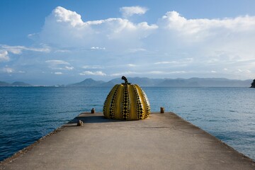 Yellow polka-dotted pumpkin sculpture by the sea