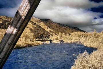 Infrared river and bridge with mountain backdrop