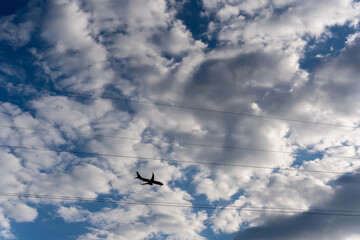 Airplane flies in the sky amidst clouds and wires. Airplane travel, airline tickets. Background.