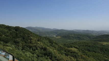 Obraz premium Scenic view of lush green hills and distant mountains.