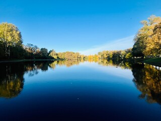 autumn trees reflection on the lake surface, blue lake reflection, golden autumn, lake in the park with quiet water as a mirror 