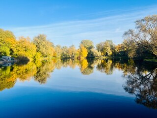 autumn trees reflection on the lake surface, blue lake reflection, golden autumn, lake in the park with quiet water as a mirror 