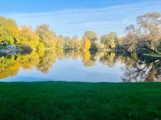 Fototapeta premium autumn trees reflection on the lake surface, blue lake reflection, golden autumn, lake in the park with quiet water as a mirror 