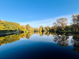autumn trees reflection on the lake surface, blue lake reflection, golden autumn, lake in the park with quiet water as a mirror 