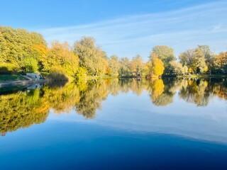 autumn trees reflection on the lake surface, blue lake reflection, golden autumn, lake in the park with quiet water as a mirror 
