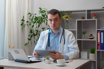 A young doctor, at his desk, receives patients.