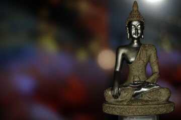 Fototapeta premium Earth Touching Buddha Statue with colorful backdrop with copy space, Bhumisparsha Buddha, Buddha in a seated meditation pose with his right hand touching the earth. 
