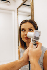 Female doctor examining child's skin. Professional dermatologist in white coat uses magnifying...