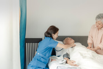 Obraz premium A healthcare woman checks the vital signs of an elderly man in bed while his wife offers comfort by holding his hand. The scene highlights compassionate care, medical attention, and emotional support.