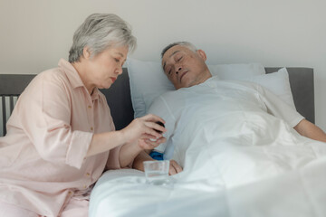 Obraz premium An elderly woman tends to her husband by administering medication while he rests in bed. The image emphasizes caregiving, compassion, and elderly support in a peaceful home setting.