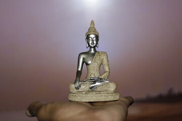 Serene Buddha Statue on hand empty colorful backdrop with copy space, yoga, meditation and...