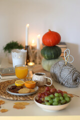 Pumpkins, various food and drinks, fall decorations, books and candles on the table. Fall hygge at home. Selective focus.