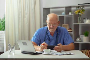 An elderly man, a doctor, in his office, at a table.