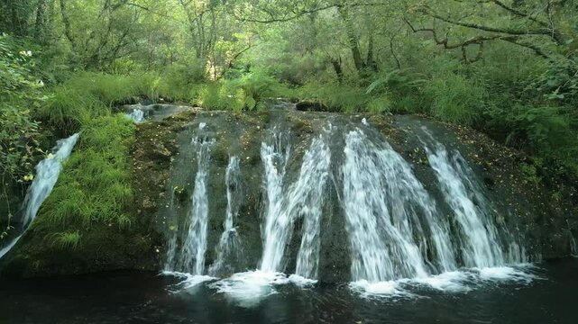 scenery of Parga Waterfall flowing from a cliff surrounded by vegetation in wilderness of Gandara