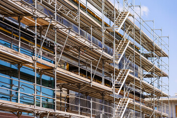 Scaffolding of High-rise Building under Construction with Ladders.   Metal Modern Scaffolding Equipment. 