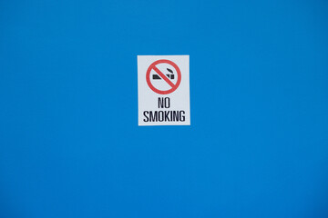 A blue wall with a sign that says no smoking