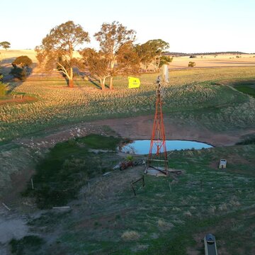 Drone shot of a mill next to a pond in rural landscape at sunset time in Marola, Spain