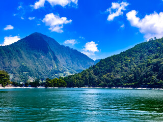 The beauty of Sarangan Lake with a mountain background and cloudy blue sky in Magetan Regency, East Java, Indonesia